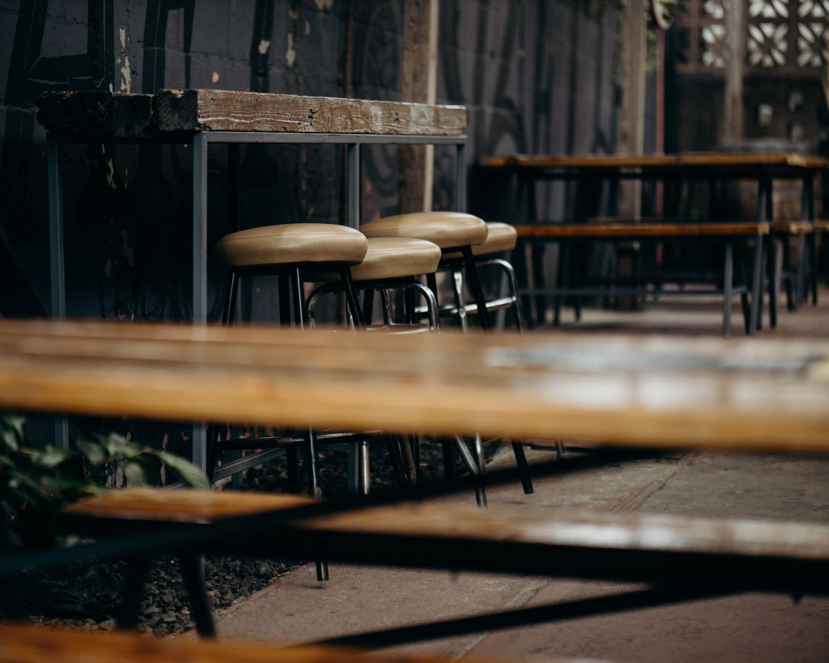 Wooden bar stools at an outdoor counter on a shaded patio